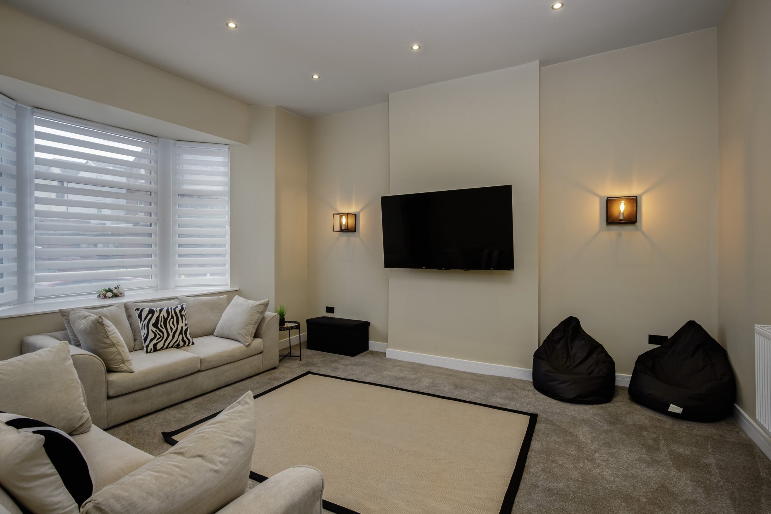 The living room at All Saints House, with cream sofas and plantation shutters